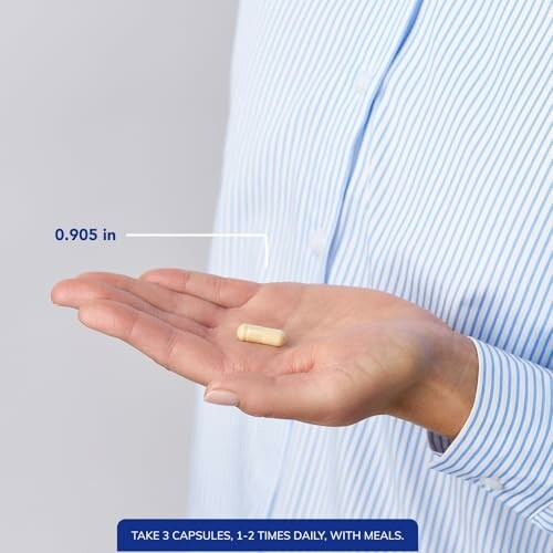 Person holding a capsule with size measurement.